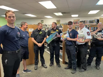 Fire and Police personnel standing holding books